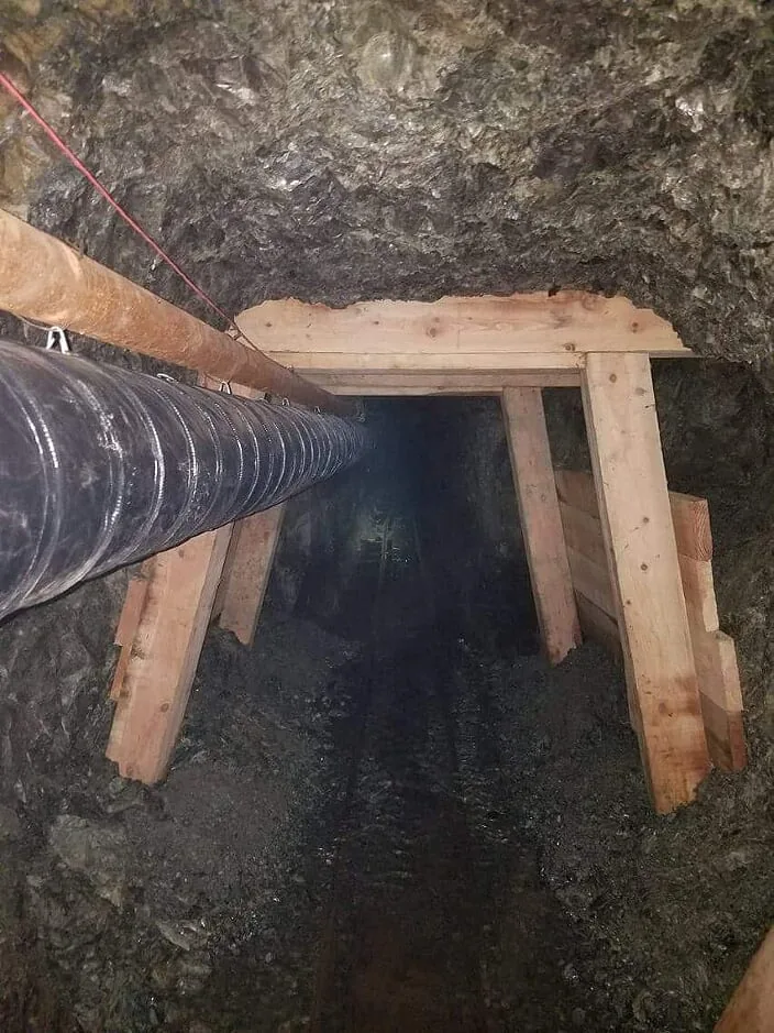 Close view of a supported mine passage and ventilation line.